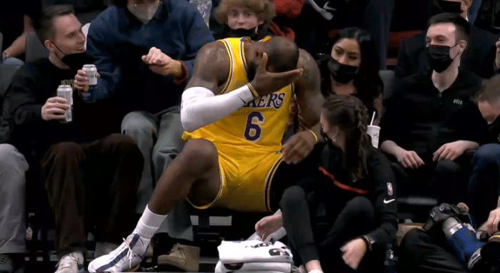 詹姆斯脑袋遭击打却没哨，捂着脑袋十分痛苦，挤开球迷直接坐进观众席